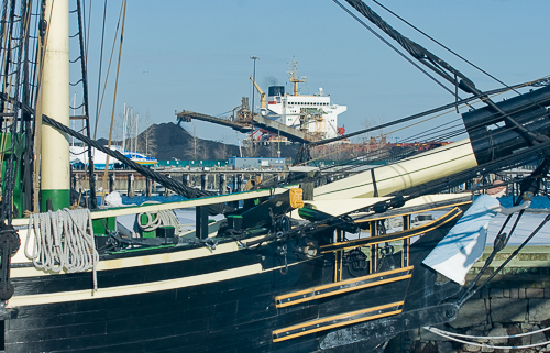Sloop Friendship, in background freighter unloads coal at electric plant