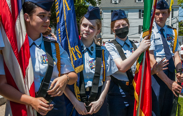 High school students in cadet uniforms, holding flags & gun