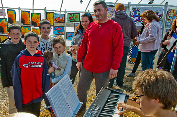 Parents and children view art and listen to music in greenhouse during fall festival at Brooksby Farm
