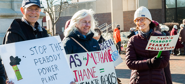 Three people holding signs at standout