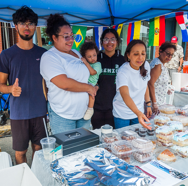 People in booth selling snacks and promoting "Welcoming Immigrant Newcomers"