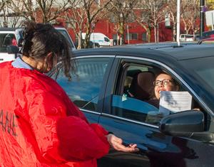 Judith Black in "gas" costume hands leaflet to motorist