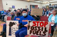 Members of audience hold signs against fossil fuels