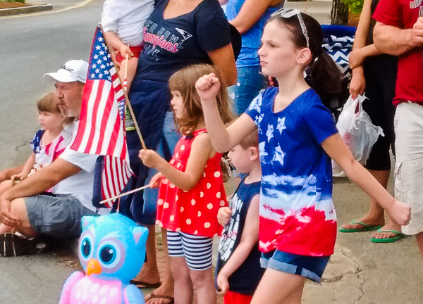 Children with flags watch, one marches in place