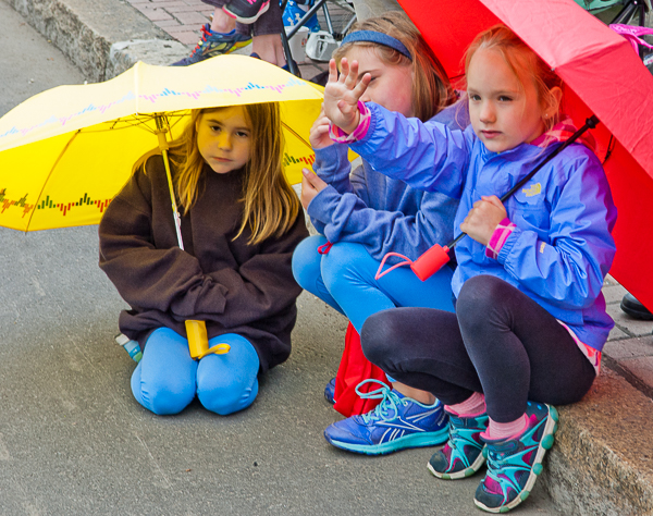 Seated girls with umbrellas watching parade