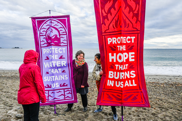 Reverend Jenna Crawford,  Minister, Unitarian Universalist Church of Marblehead looks at banners held by Judith Black and Reverend Kendra Ford