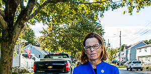 Sally Kerans, facing viewer, with Danvers homes behind her