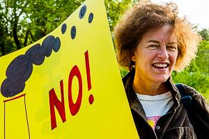 Woman holds sign with smokestack and "NO!"