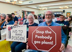 Susan Smoller and Ron Smoller hold signs at hearing